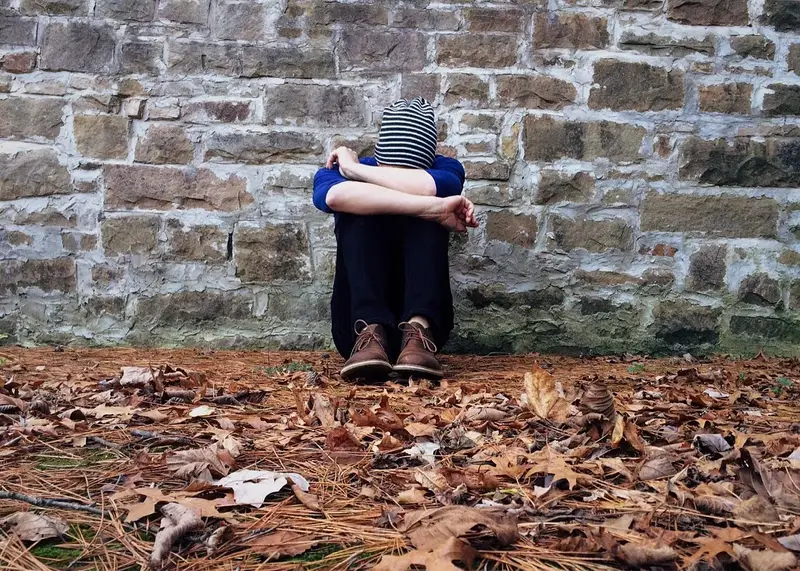 A child sitting alone hugging their knees — the isolation and distress experienced by children in harmful religious environments
